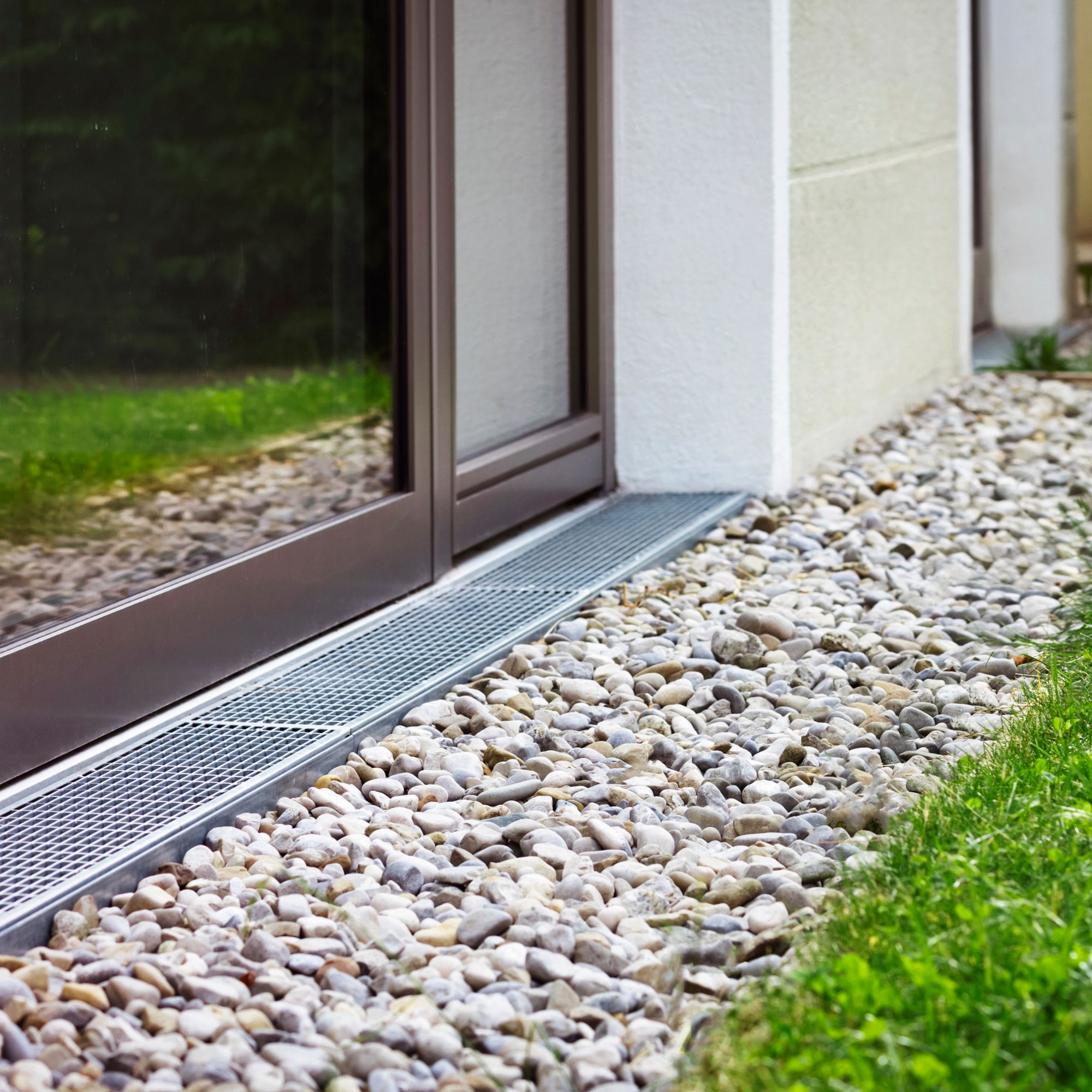 French drain with gravel running between lawn and house