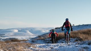 Two mountain bikers riding in the snow