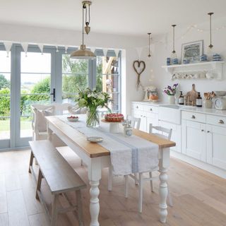 white country cottage kitchen with farmhouse table and patio doors to garden