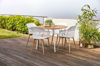 dark wood decking patio with small dining table and white chairs