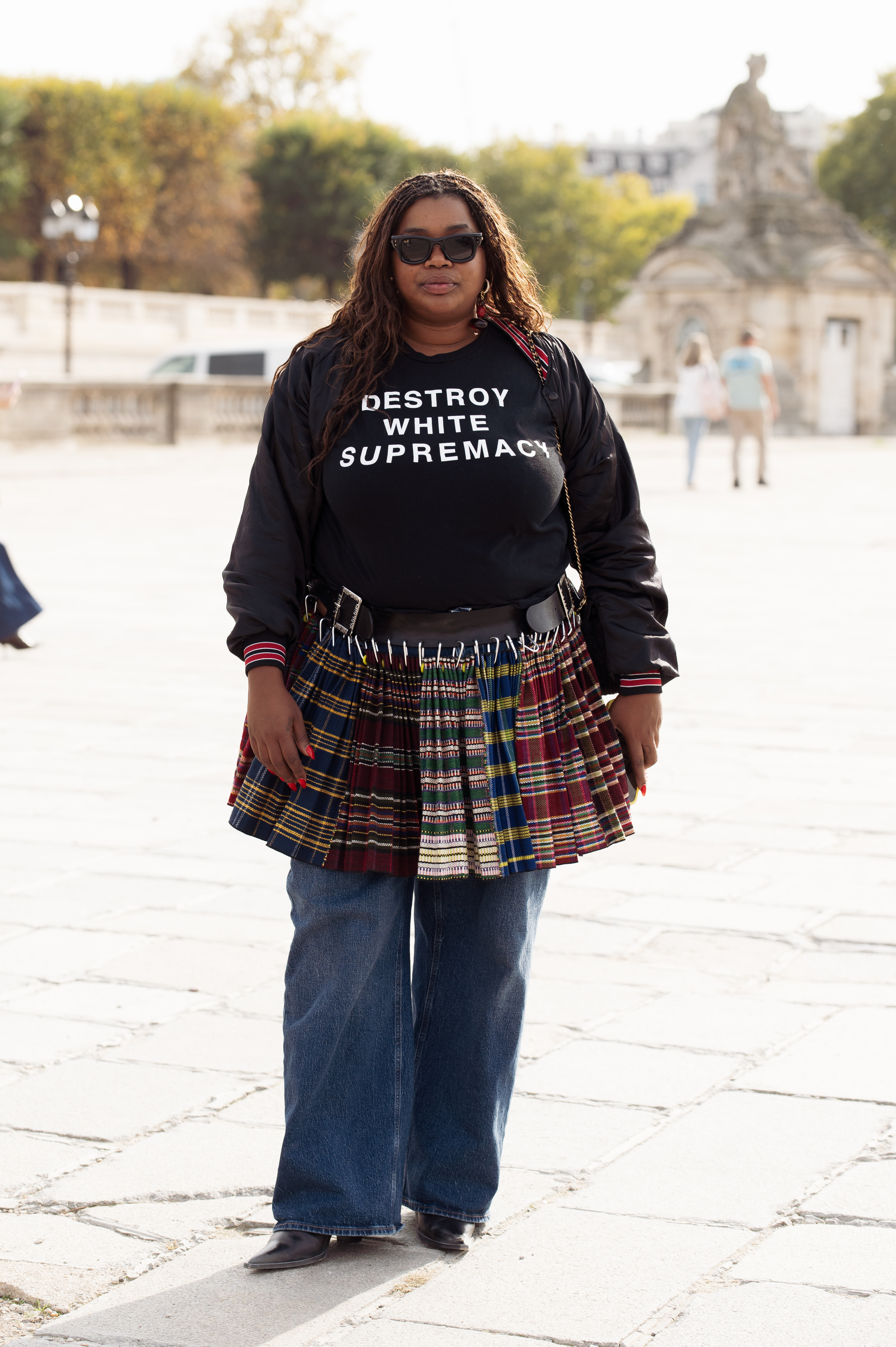 a woman wearing a black longsleeve shirt, mini kilt skirt, and blue jeans