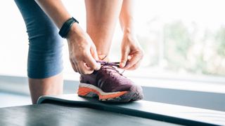 Woman's hands lacing up running trainers on a treadmill