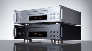 Angled view of two TEAC PD-507T CD transports stacked together, one silver and one black. Both are on a reflective dark surface against a pale grey background