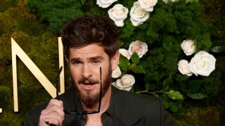 Andrew Garfield putting his glasses on while posing at the Golden Globes