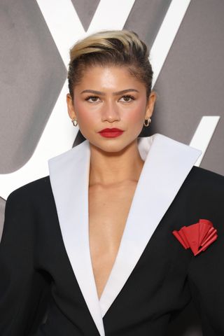 A closeup of Zendaya wearing red lipstick and gold hoop earrings