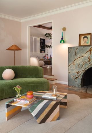 Pale pink living room with green sofa na grey marble fireplace