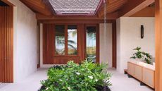outdoor paved courtyard with rocky garden and ferns with timber window frames and ceiling beams with rain chain