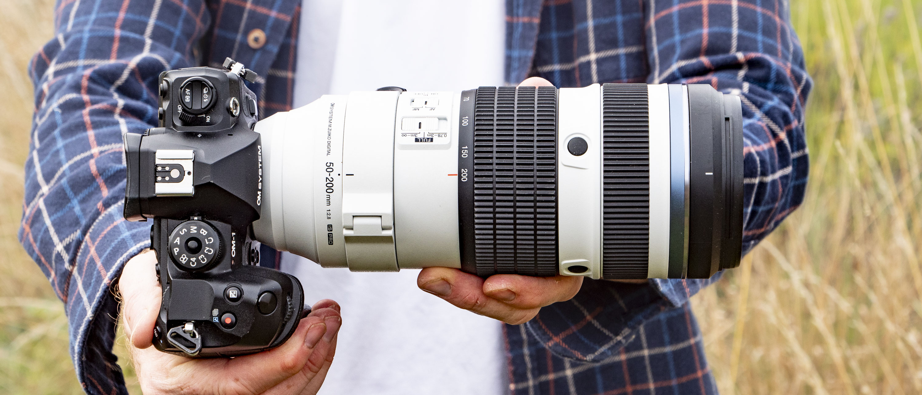 OM System M.Zuiko Digital ED 50-200mm F2.8 IS Pro lens in photographer&#039;s hands