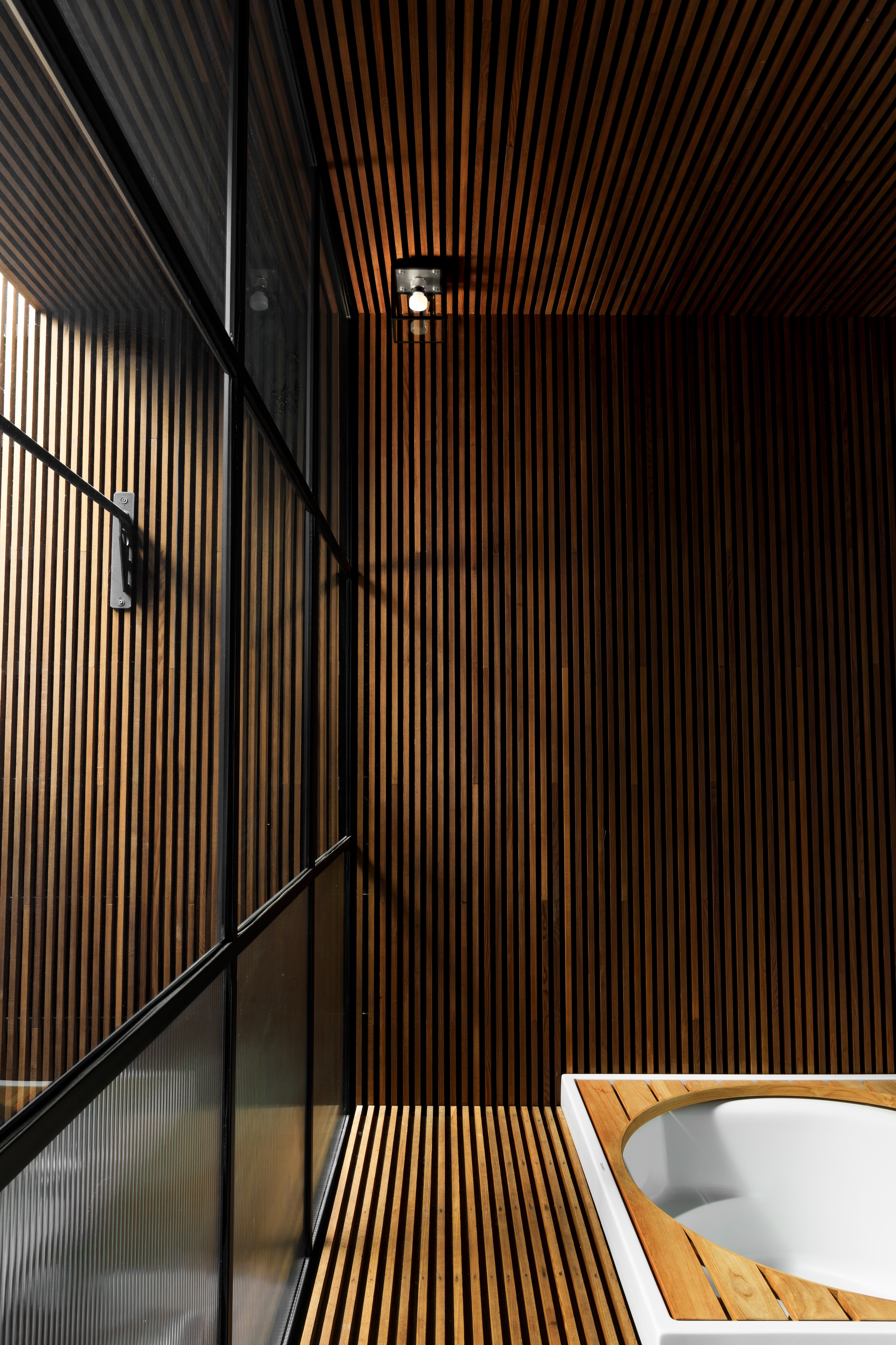 A dark wood-panelled bathroom with a small light
