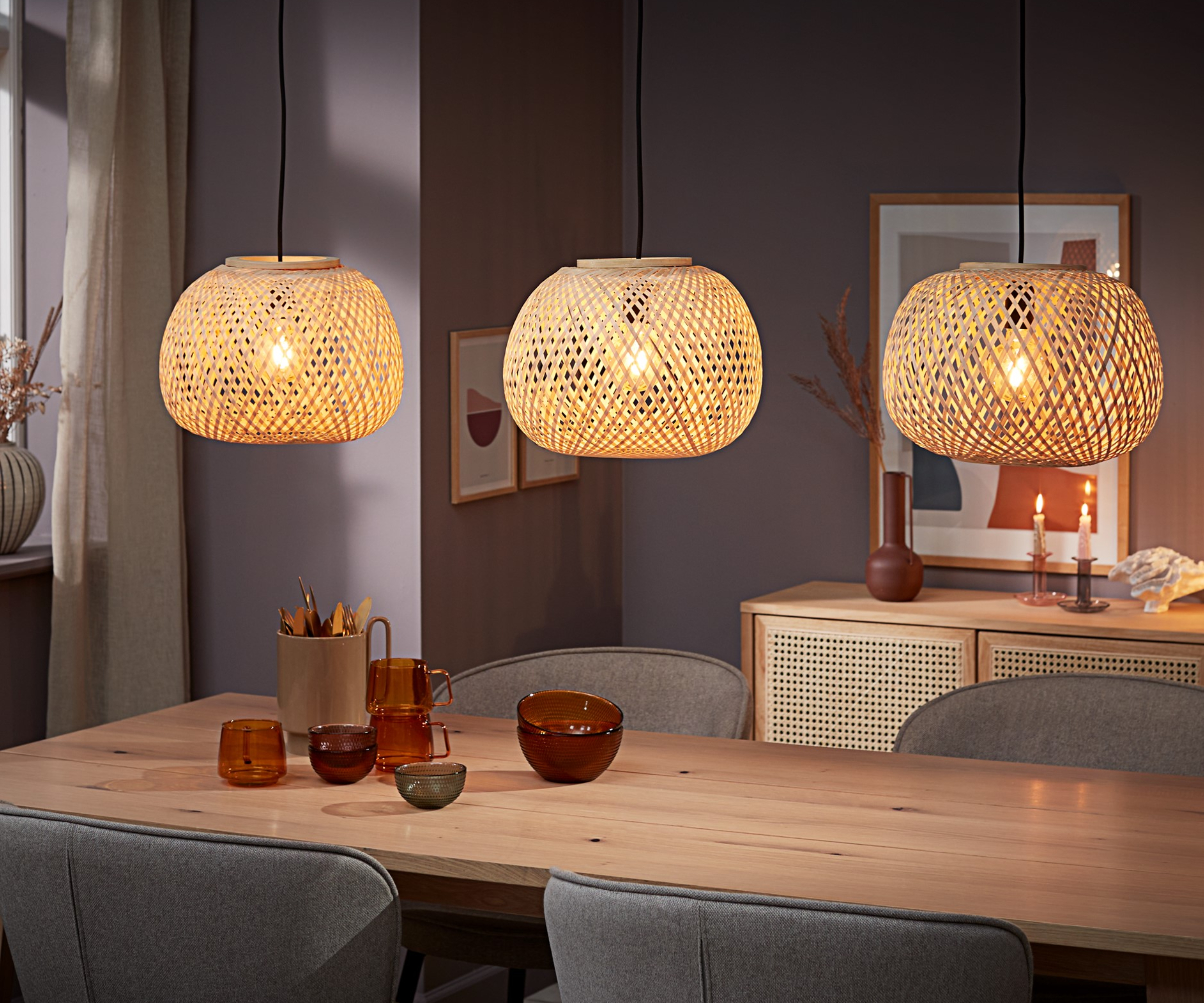 rattan pendants over wooden dining table in room with soft grey walls