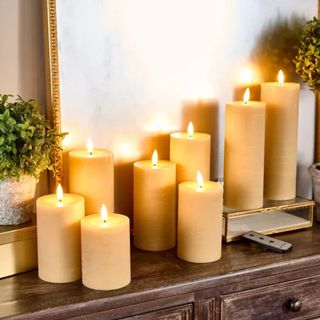 A set of LED pillar candles turned on on aa wooden sideboard