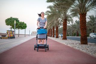 Asian woman running with a pram outdoors in sunset