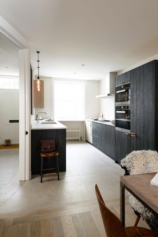 A small kitchen with galley layout with stained wood cabinets in a matt finish and marble countertops