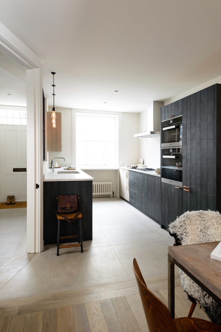 一个小厨房，厨房布局有哑光染色的木质橱柜和大理石台面