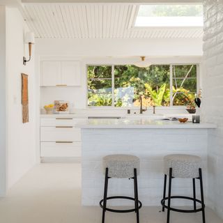 Kitchen with white painted walls and bar stools in front of counter