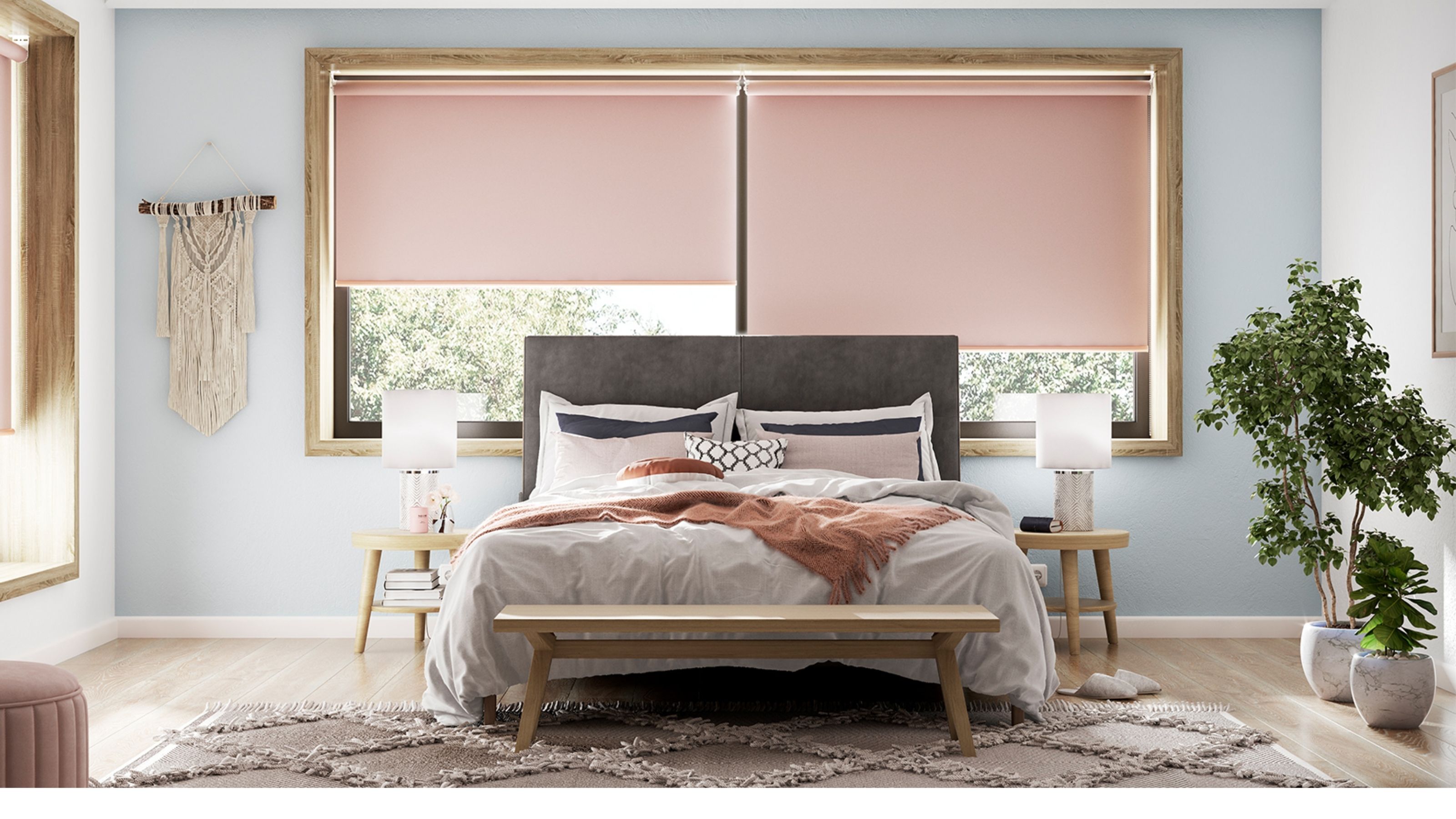 Image of a light blue bedroom with pink double roller blinds on the windows. There is a gray bed with pink and gray bedding and boho decor in the room.