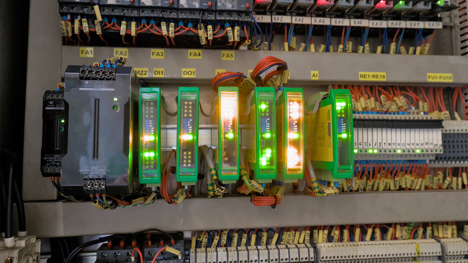 Programmable logic controllers (PLCs) pictured inside an industrial cabinet unit with LEDs, power supply, relays, and organized wire ducts.