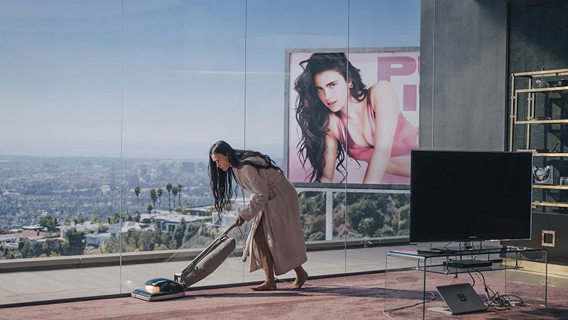 Demi Moore hoovering her apartment against a skyline backdrop