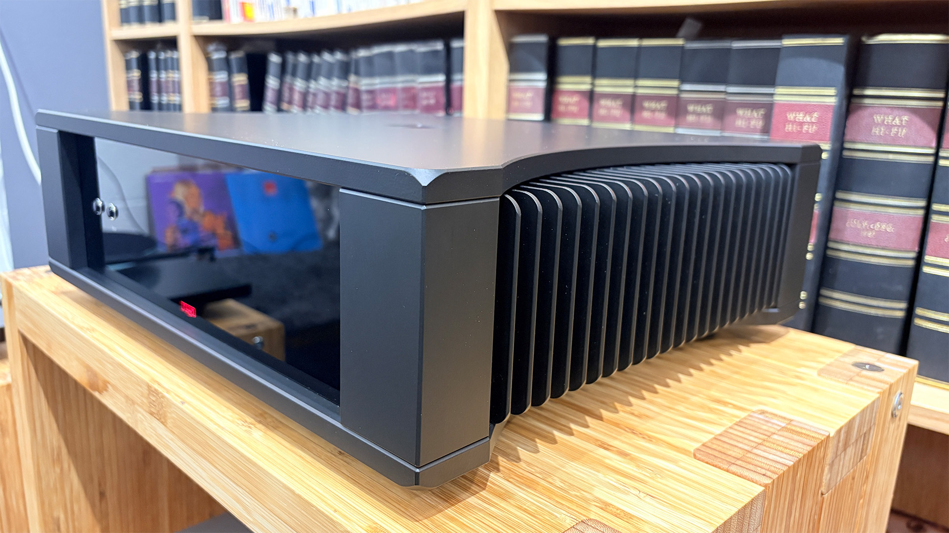 Rega Solis power amplifier on wooden hi-fi rack in front of bookcase slight angle from right