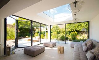 modern Apropos orangery with a roof light and sliding doors, and a grey sofa and foot stools
