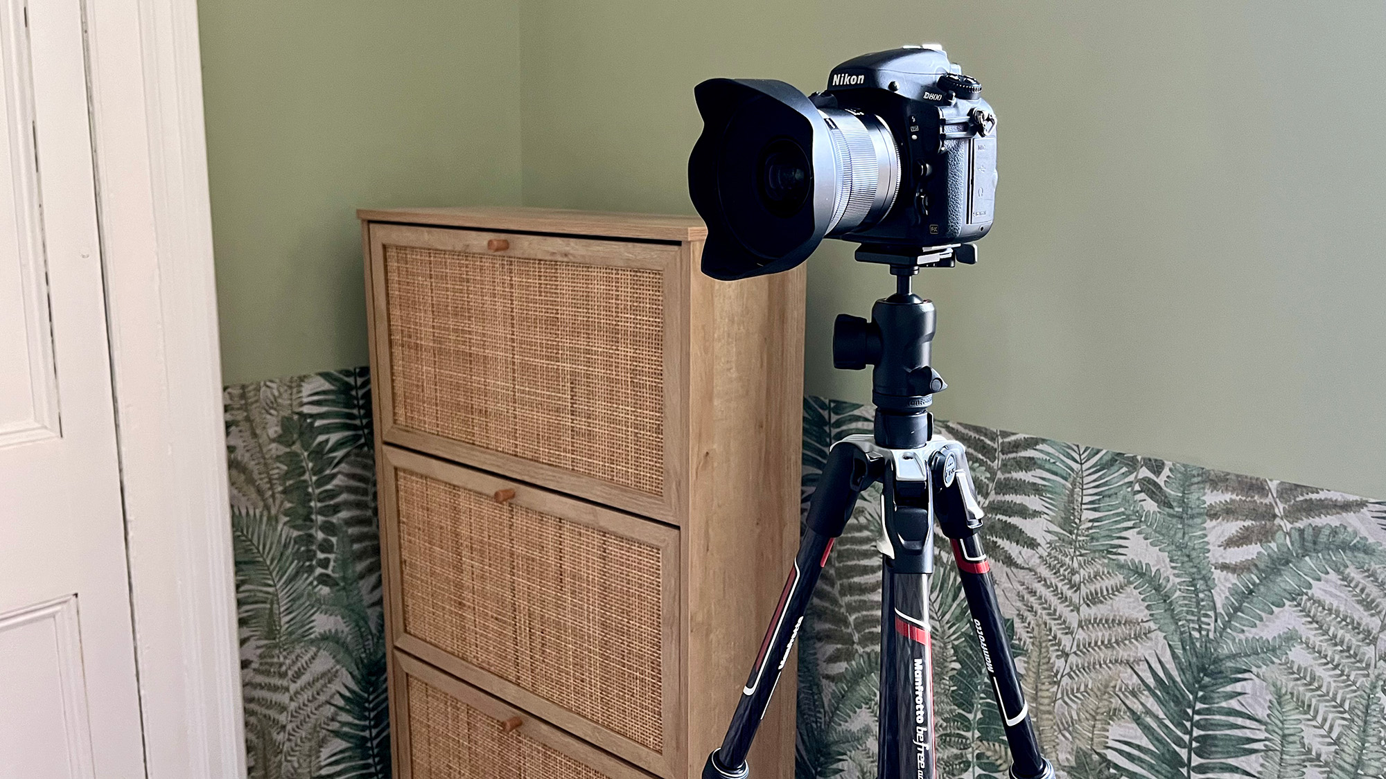 Image of Nikon camera on a tripod in front of a soft green wall