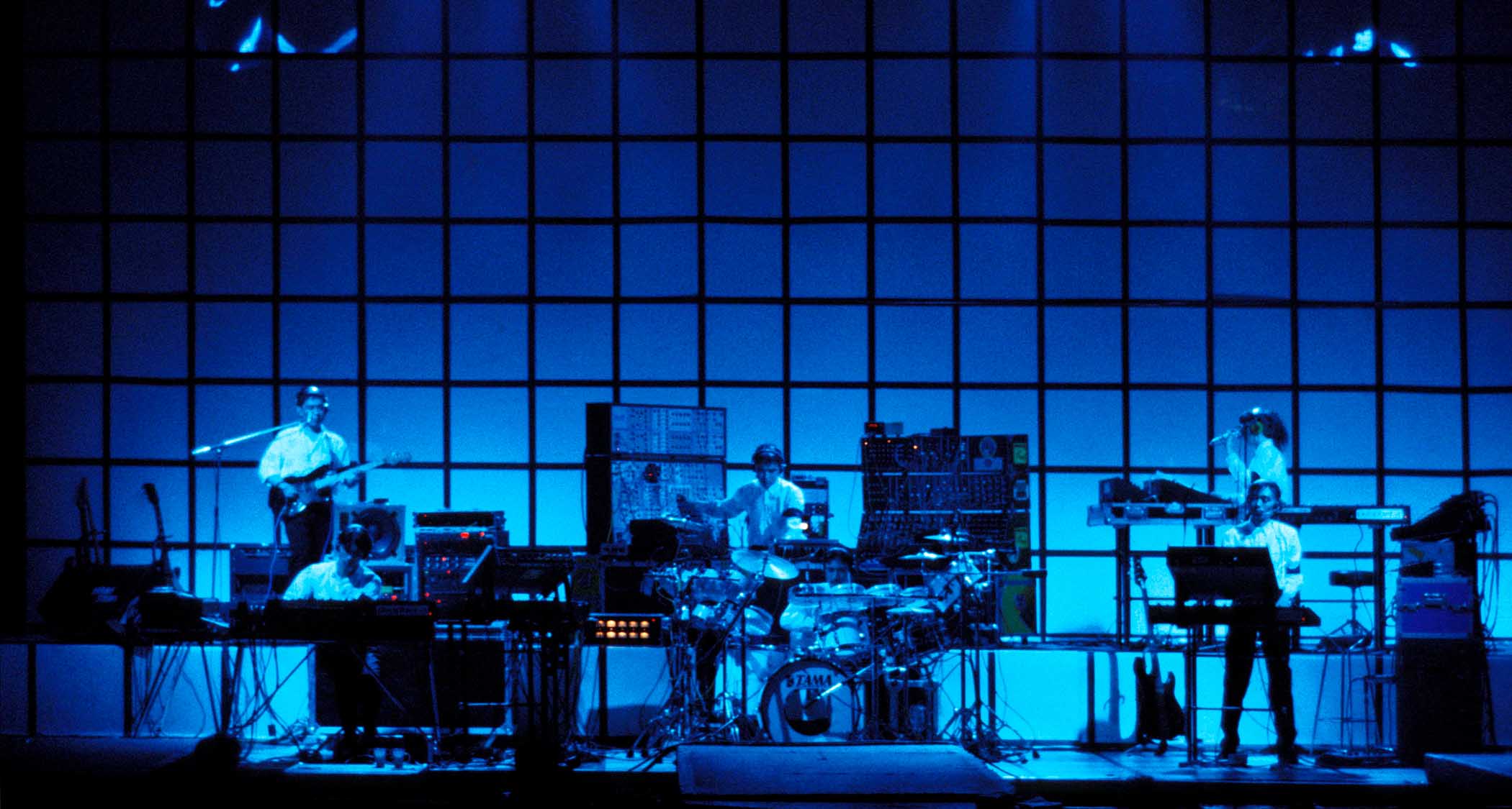 Yellow Magic Orchestra perform in a stage lit up in blue at London's Hammersmith Odeon in 1980.