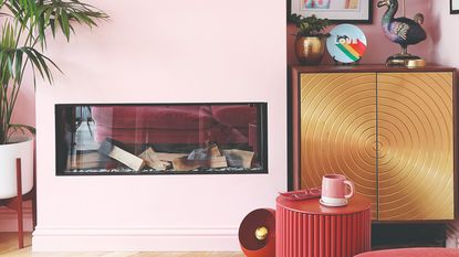 A colour-drenched pink living room with a fireplace and a bookcase