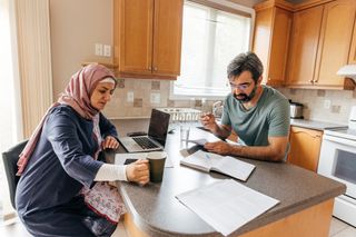 couple at home in kitchen looking at their household bills