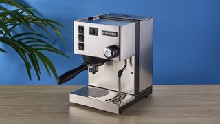 Rancilio Silvia in Stainless steel on a wooden worktop with a blue wall in the background.