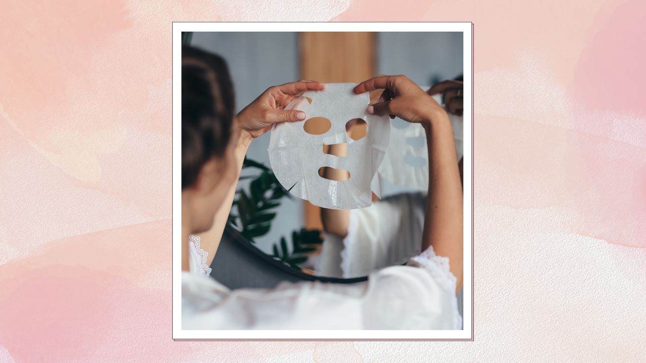 A close up of a woman with pink nails holding up a sheet mask in the mirror, about to apply it to her face/ in a pink and orange watercolour template