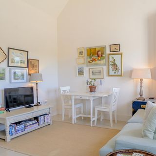 tv room with white wall and picture frame and white table and chairs and television