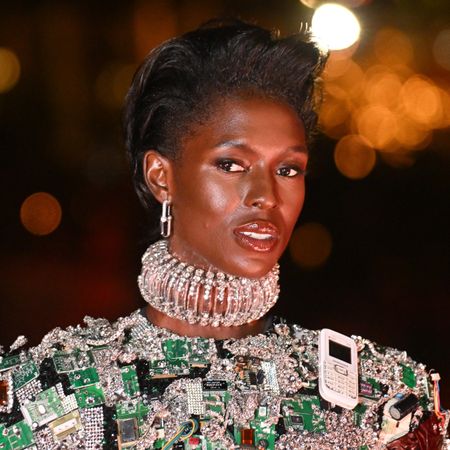 a black woman with short, black hair poses during a runway show
