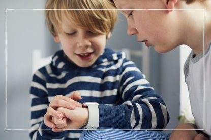 two boys looking at a wristwatch together as part of our best kids' watches round up