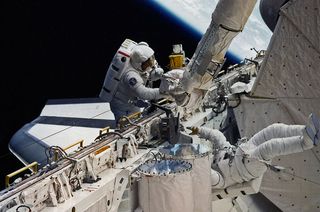 STS-51D mission specialists Jeffrey Hoffman and David Griggs work outside the space shuttle Discovery during NASA's first unplanned spacewalk in April 1985.