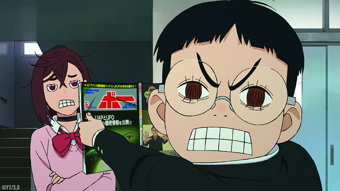 DAN DA DAN; grimacing boy shows magazine to grimacing girl
