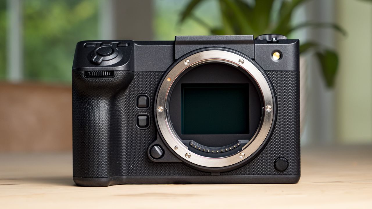Fujifilm GFX100 II on a wooden table front of the camera with no viewfinder and no lens attached