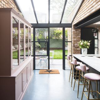 Glass roof kitchen with blush cabinets and pink bar stools