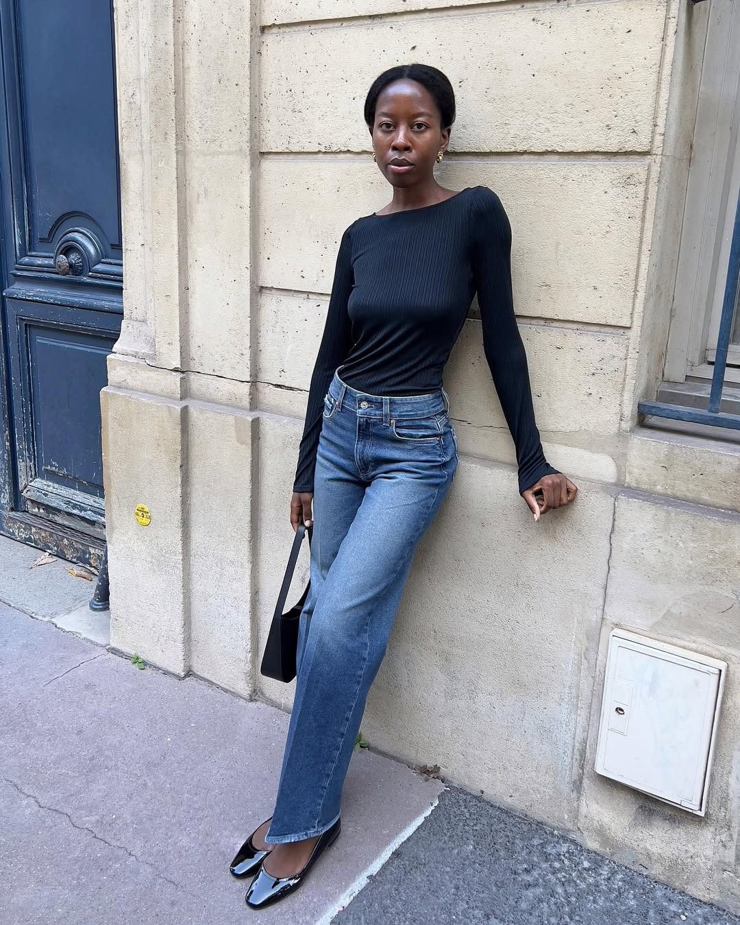 Influencer @sylviemus_ wears high-wasted blue jeans with a blue boatneck top and patent leather flats.