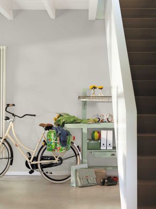 Dulux Goose Down used in a hallway room, with a bicycle and table to the left, and dark wooden stairs to the right