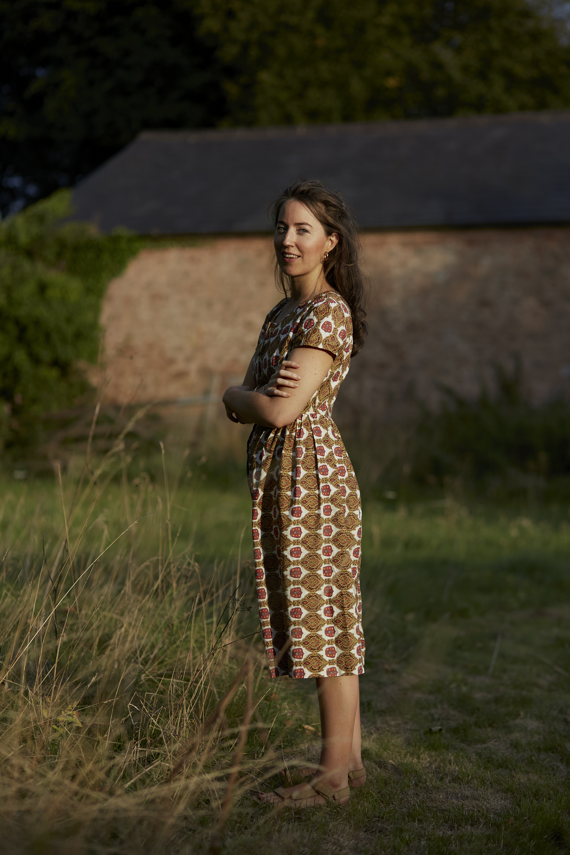 Emily Cameron in a brown dress in a field