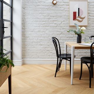 dining area with white brick wall wooden dinning table and chairs and wooden flooring