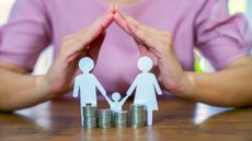 Coins and paper cut out human figures standing on a dining table.