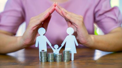 Coins and paper cut out human figures standing on a dining table.