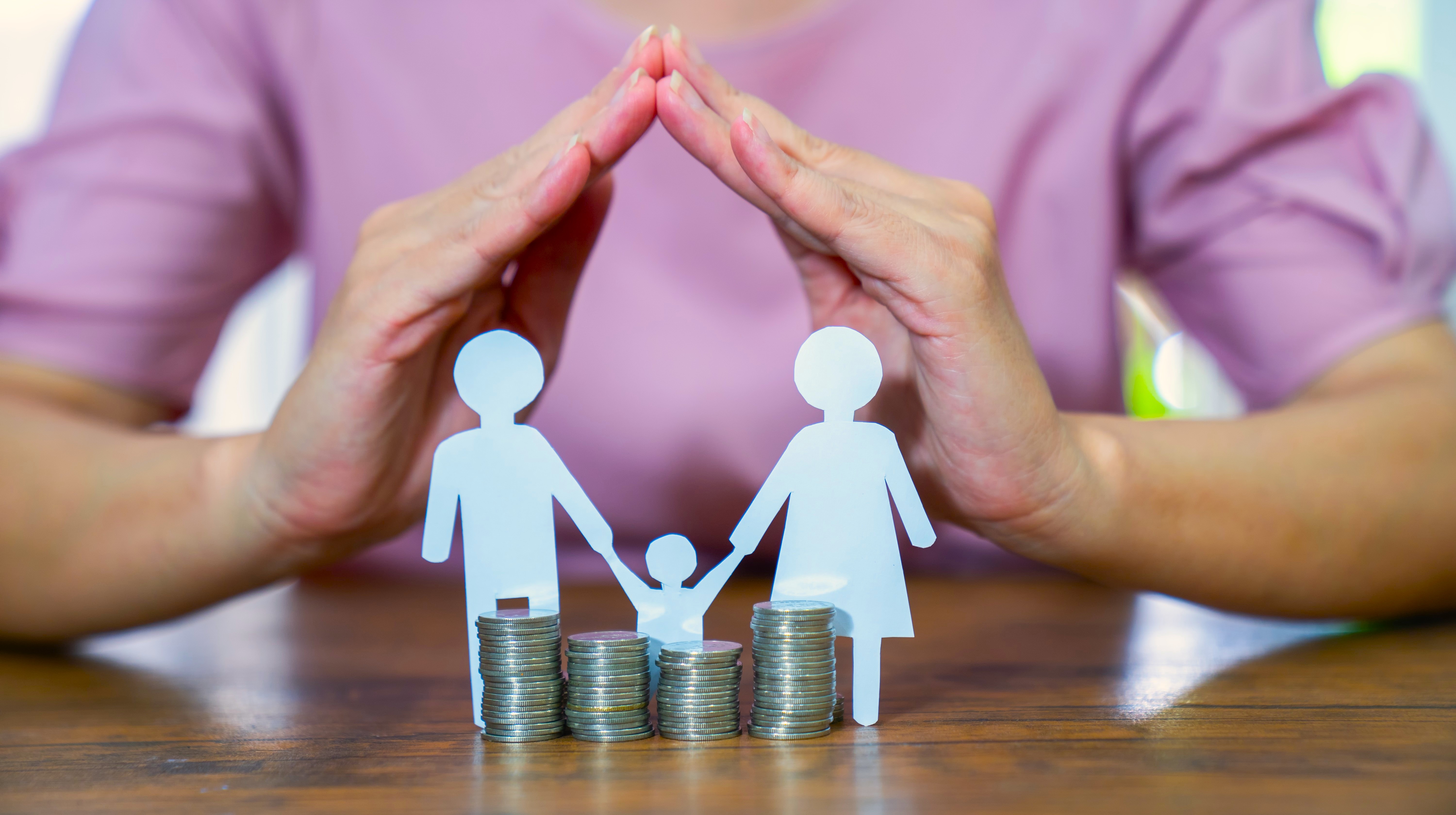 Coins and paper cut out human figures standing on a dining table.