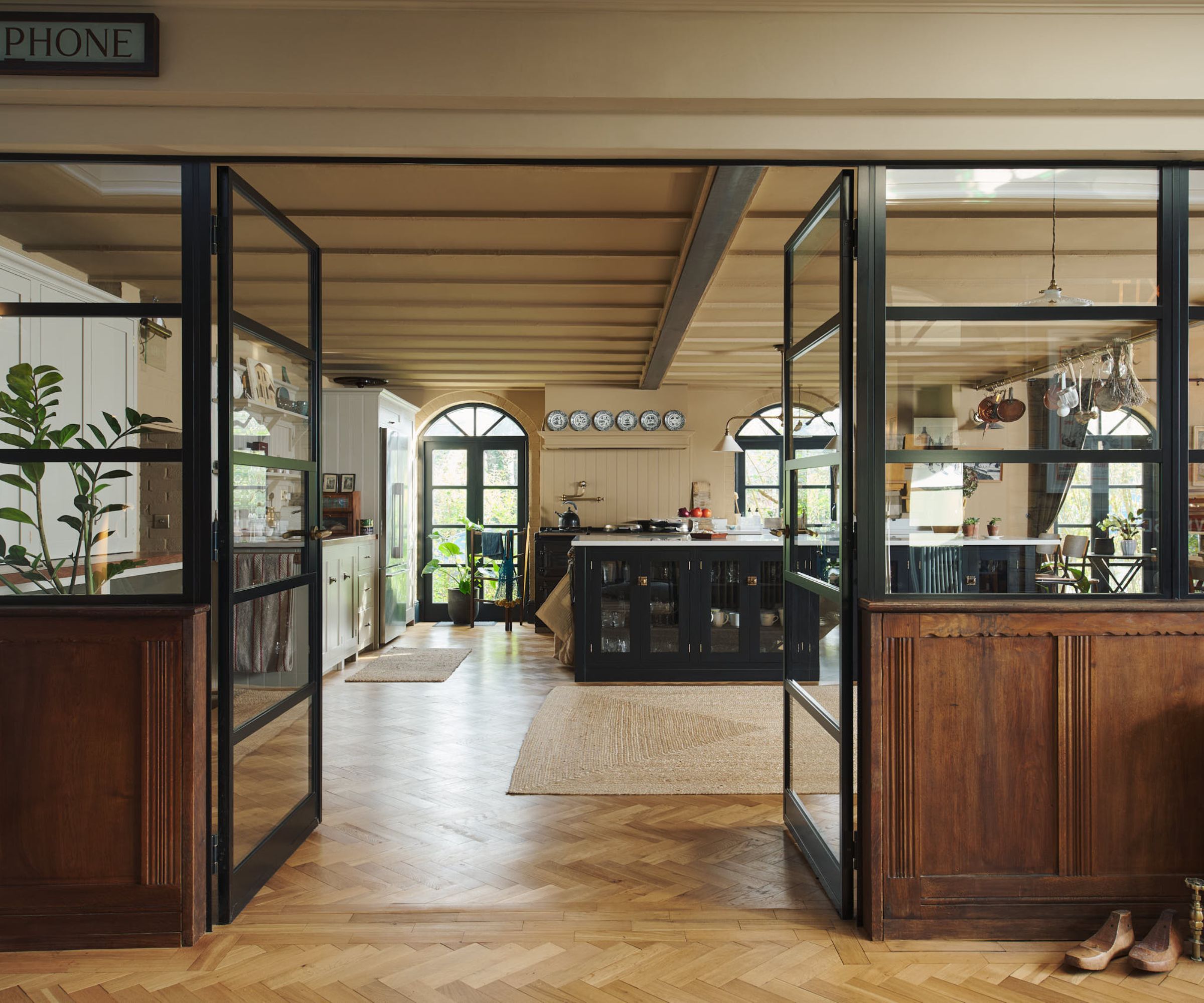 An open plan kitchen and dining space divided by glazed partitions