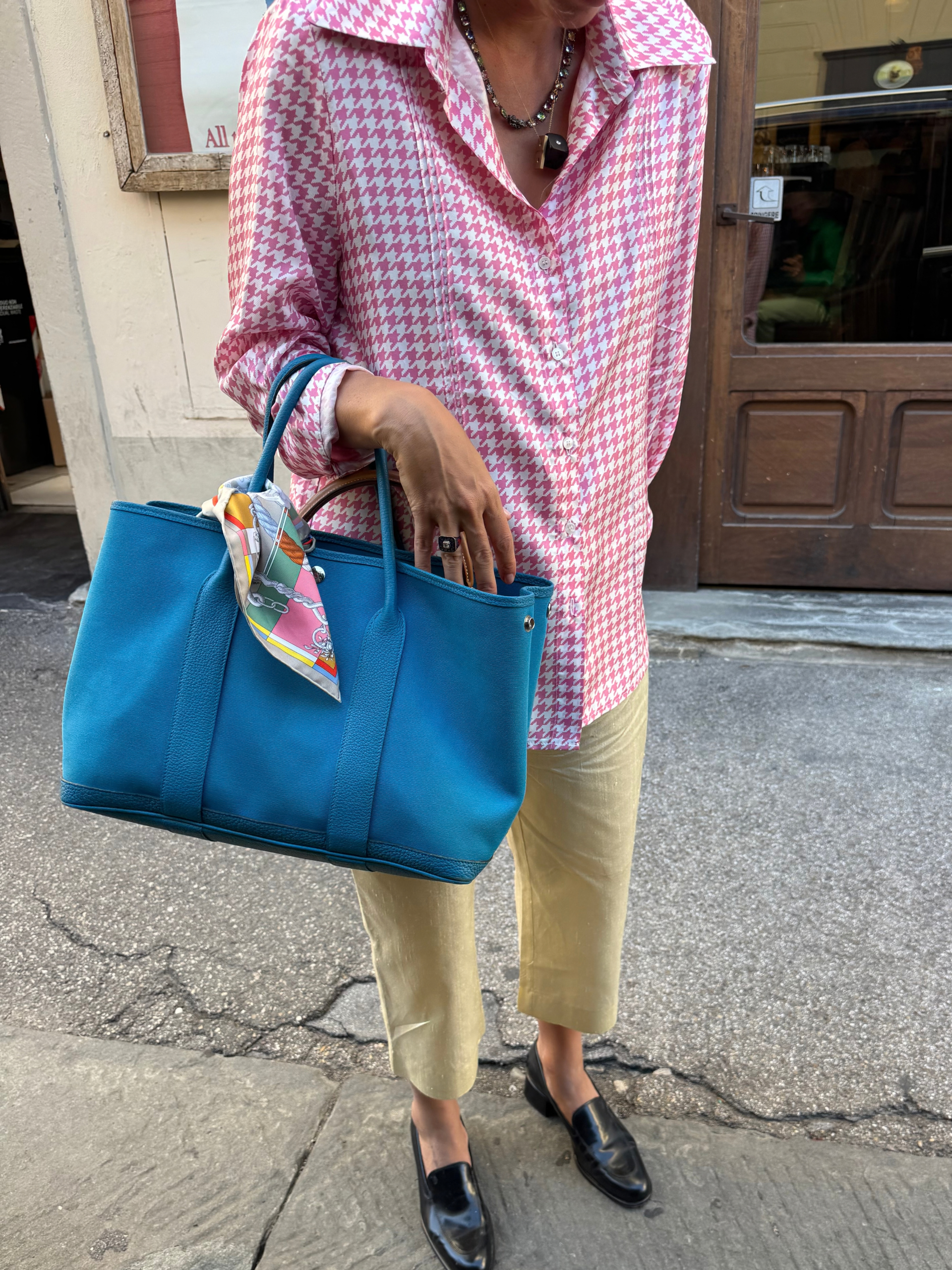blanco miro wears a pink check shirt, yellow trousers, leather loafers and a blue tote bag
