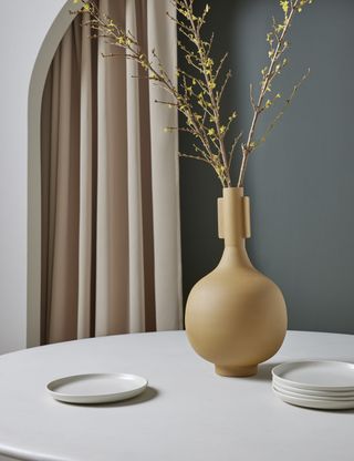 light brown sculptural vase on a dining table