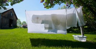 clothes line outside on a spring day showing bedding hung out to dry to demonstrate the recommended steps to washing a mattress protector