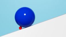 small red ball holding up a big blue ball on a white incline with a teal background