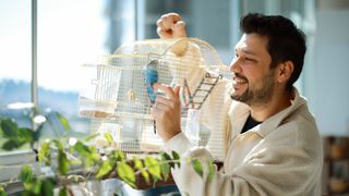 Man holding bird cage with budgie